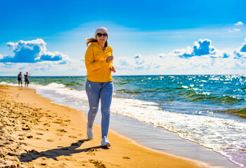 Beautiful mid adult woman running on sunny beach