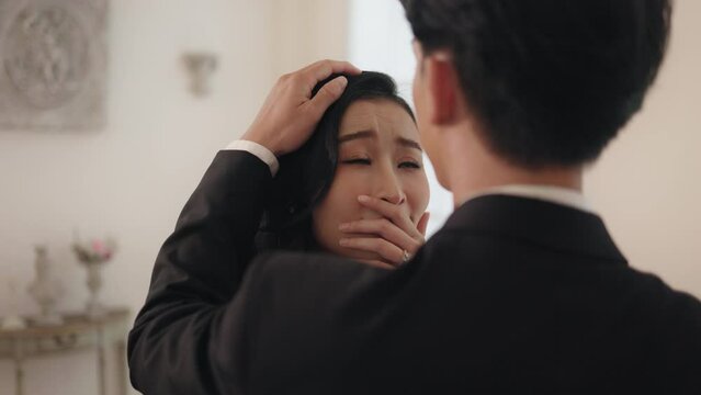Emotional Asian bride crying tears of joy while groom comforts her during wedding ceremony.