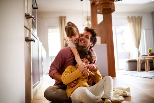 Happy young dad having fun with his kids on the floor at home