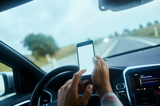 Close up man hands using smartphone at wheel during drive on freeway