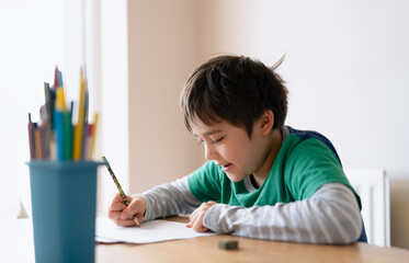 Education concept,School kid using pencil drawing or sketching on paper,Portrait  boy siting on...