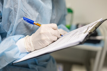 Close-up The anesthesiologist records the progress of the operation on a tablet while standing in...
