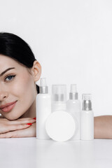Obraz na płótnie Canvas Woman showing cosmetic products branding mockup. Daily skincare and body care routine. Natural cosmetic cream, serum, white bottles packaging, bio organic product.