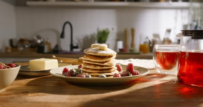 Side view of pancakes with berries, butter and sugar powder in kitchen, slow motion. No people, advertising cinematic. Art of healthy tasty food, gluten-free recipes and delectable gluten-free options