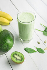 Green detox smoothie, blended vegetarian drink in a glass from spinach, apple, banana, kiwi,...