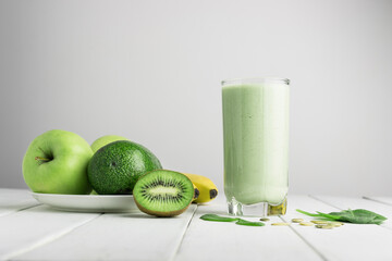 Green detox smoothie, blended vegetarian drink in a glass from spinach, apple, banana, kiwi,...