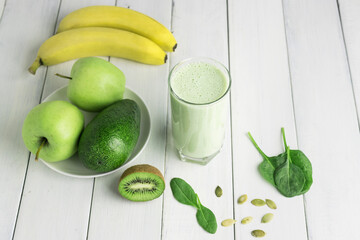 Green detox smoothie, blended vegetarian drink in a glass from spinach, apple, banana, kiwi,...