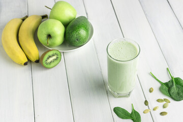 Green detox smoothie, blended vegetarian drink in a glass from spinach, apple, banana, kiwi,...