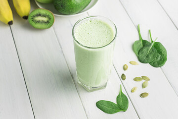Green detox smoothie, blended vegetarian drink in a glass from spinach, apple, banana, kiwi,...