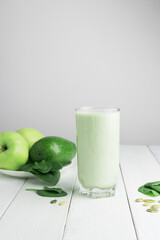 Green detox smoothie, blended vegetarian drink in a glass from spinach, apple, avocado and seeds on...
