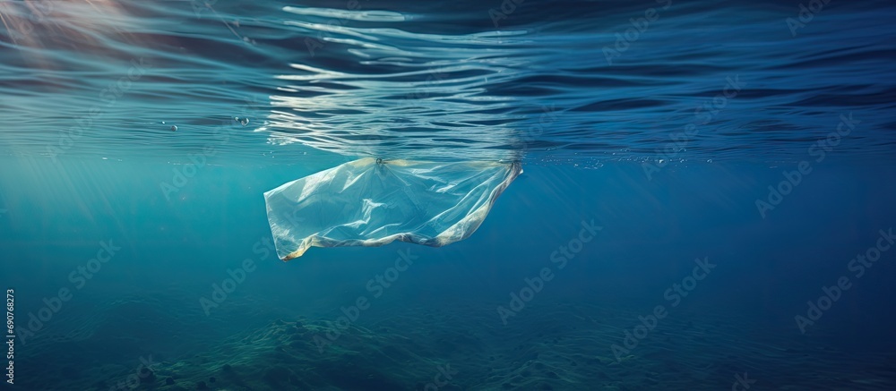 Poster underwater pollution a discarded plastic carrier bag drifting in a tropical blue water ocean. copysp