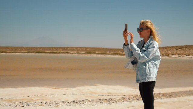 Female traveler capturing vast expanse of Salty Lake Tuz in Turkey with her mobile phone. Panoramic view shows mesmerizing white crystallized surface of lake with salt.