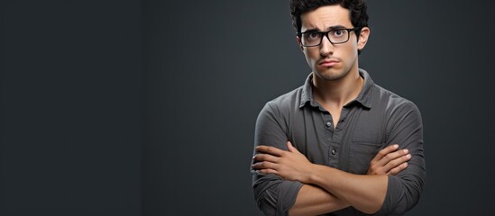 Young hispanic man wearing casual clothes and glasses skeptic and nervous disapproving expression on face with crossed arms negative person. Copyspace image. Header for website template