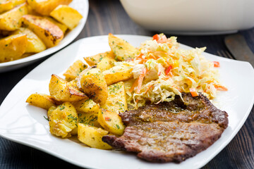 Roast pork neck served with baked potatoes.