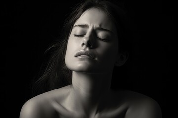 A black and white photo of a woman with her eyes closed. Can be used to portray relaxation, meditation, or peace