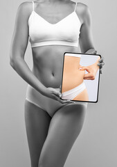 Girl pulls the skin on the abdomen, showing the body fat. Treatment and disposal of excess weight,...