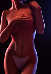 Slim sexy woman in lingerie on a dark background. Her body is illuminated with blue and red lights.
