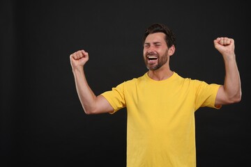 Emotional sports fan celebrating on black background