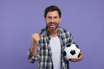 Emotional sports fan with soccer ball on purple background