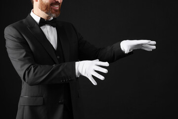 Magician in suit on black background, closeup