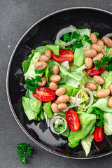 white bean salad green lettuce, tomato, onion, salad dressing ready to eat healthy eating cooking appetizer meal food snack on the table copy space food background rustic top view keto or paleo diet