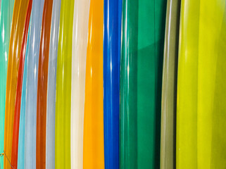Horizontal coseup of colorful surfboards stacked together in a rainbow of colors.