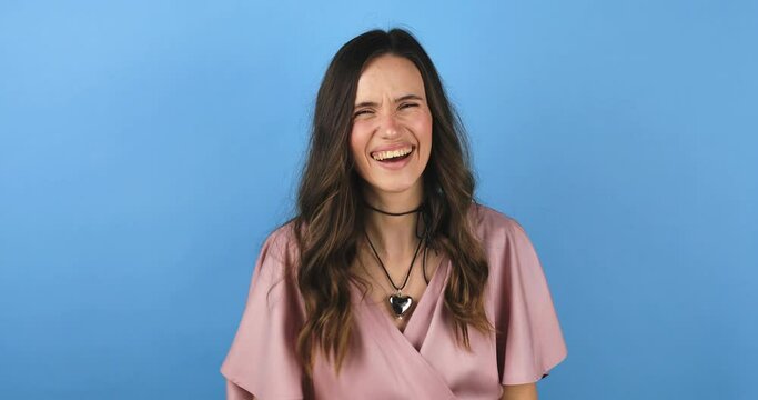 Young excited cheerful funny brunette woman look camera laugh smiling watch comedy movie, listening joke, pointing index finger on you isolated on blue background studio portrait.