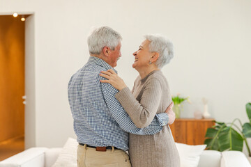 Keep moving. Romantic senior mature couple dancing to music together at home. Happy smiling family retired man woman husband wife having fun enjoying time together. Family moment love care
