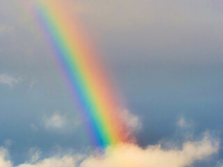 A bright rainbow shining through stormy cumulonimbus clouds during unsettled weather above the...