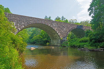 Fototapeta na wymiar Stone Arch Bridge Over a Quiet River