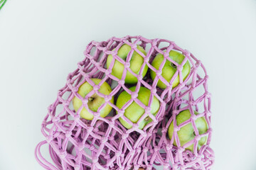 Five green apples in a bag on a white background