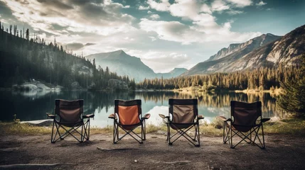 Papier Peint photo autocollant Réflexion A row of lightweight, high-performance camping chairs set up near a tranquil alpine lake, reflecting the surrounding mountain peaks
