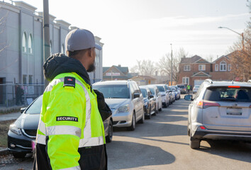 Security guard conducting access control, traffic control, and parking enforcement duties around a...