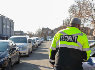 Security guard conducting access control, traffic control, and parking enforcement duties around a community building.