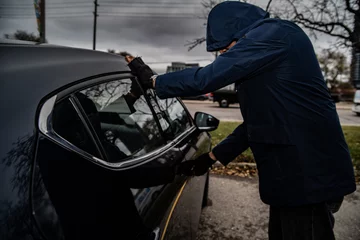 Abwaschbare Fototapete A car thief is breaking into a car in broad daylight in Toronto, Ontario, Canada. © Flex_Point_Security