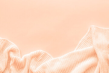 Knitted blanket on peachy background. Top view, flat lay, copy space. Color of the year 2024 -...