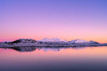 Snowy mountains, sea bay, reflection in water at sunset in winter. Lofoten islands, Norway....