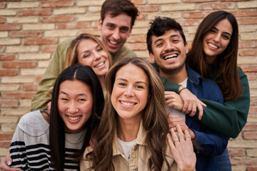Multiracial group of friends outdoors smiling and having fun. International students happy together looking at camera. Portrait of young people from generation Z . Intercultural relations, community. - obrazy, fototapety, plakaty