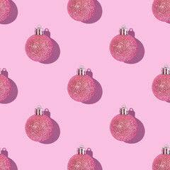 Pink shiny Christmas baubles on a pink pastel background. Creative Christmas pattern