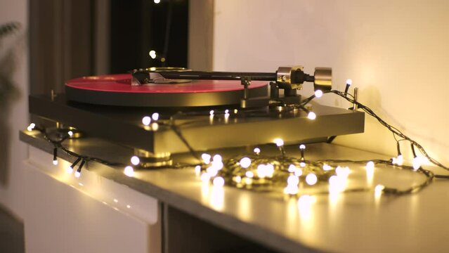 A vinyl record spins in the modern gramophone music player and plays an old disco. Close-up shot of custom vinyl turntable player with carbon tonearm. Pink vinyl record