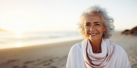 Smiling attractive beautiful caucasian senior mature woman posing at the beach looking at the camera - obrazy, fototapety, plakaty