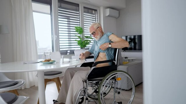 Diabetic senior man on wheelchair checking blood sugar level with fingerstick urbaning glucose meter.