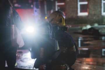 Group of fire men in protective uniform during fire fighting operation in the night city streets,...