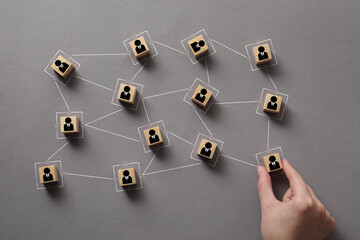 Teamwork. Woman arranging wooden cubes with human icons linked together symbolizing cooperation at...