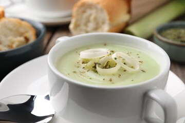 Delicious cream soup with leek and spices in bowl on table, closeup