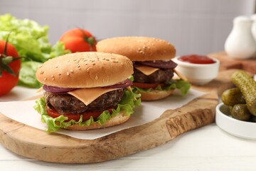 Tasty hamburgers with patties, cheese and vegetables served on white wooden table, closeup