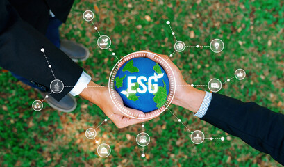 Two businessmen's hand holding planet Earth together symbolize ESG business partnership commitment...