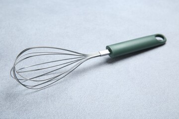 Metal whisk on gray table. Kitchen tool