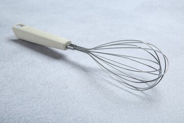 Metal whisk on gray table. Kitchen tool