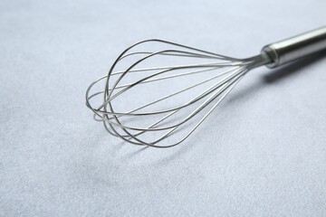 Metal whisk on gray table, closeup. Kitchen tool